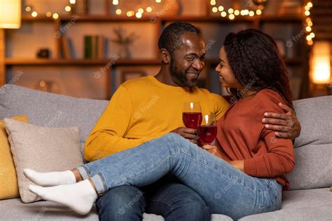 black couple cuddling|Beloved African American couple cuddling and smiling on couch.